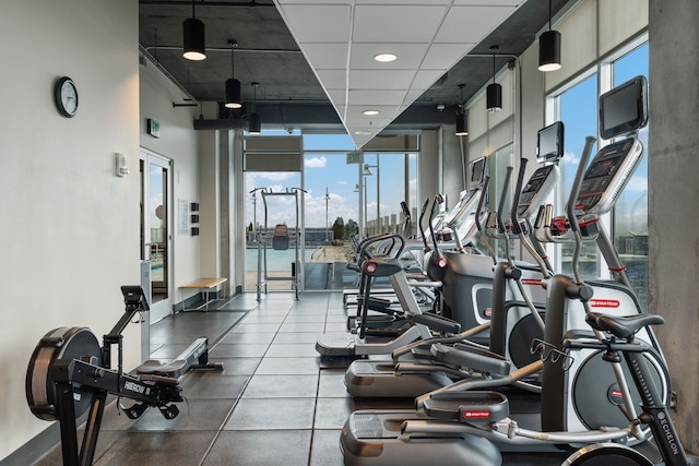 exercise room featuring a paneled ceiling and a healthy amount of sunlight