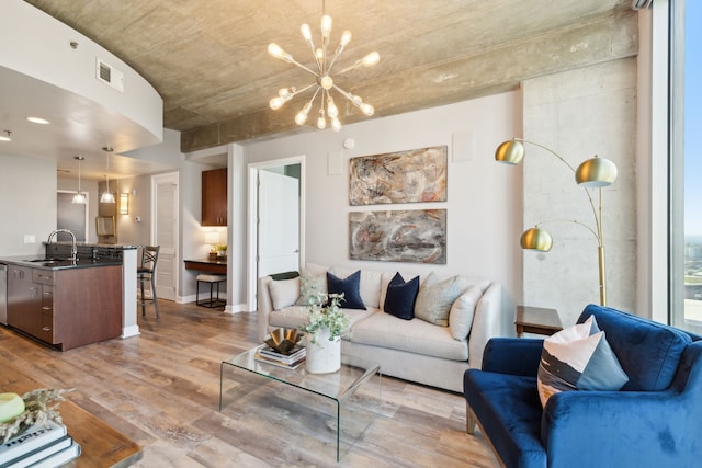 living room featuring light hardwood / wood-style flooring, sink, and a notable chandelier