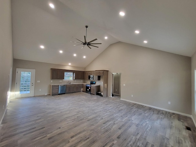 unfurnished living room featuring ceiling fan, sink, light wood-type flooring, and high vaulted ceiling