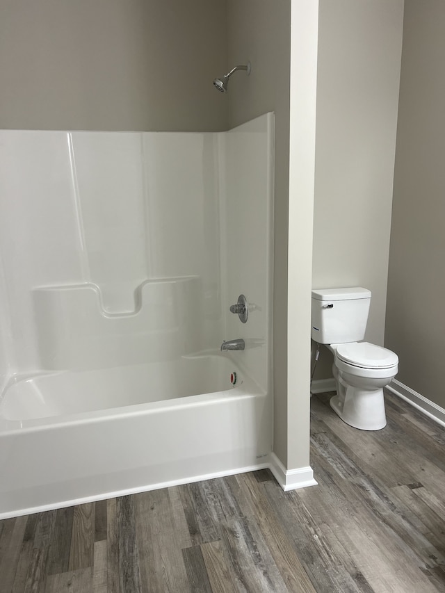 bathroom featuring toilet, hardwood / wood-style floors, and shower / washtub combination