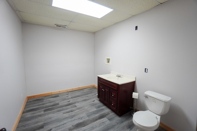 bathroom featuring vanity, a drop ceiling, wood-type flooring, and toilet