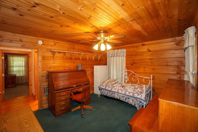 carpeted bedroom featuring wood walls, ceiling fan, and wooden ceiling