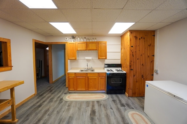 kitchen with wood-type flooring, sink, white fridge, a paneled ceiling, and range with gas cooktop