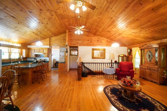 living room with wooden walls, light hardwood / wood-style flooring, wooden ceiling, sink, and ceiling fan