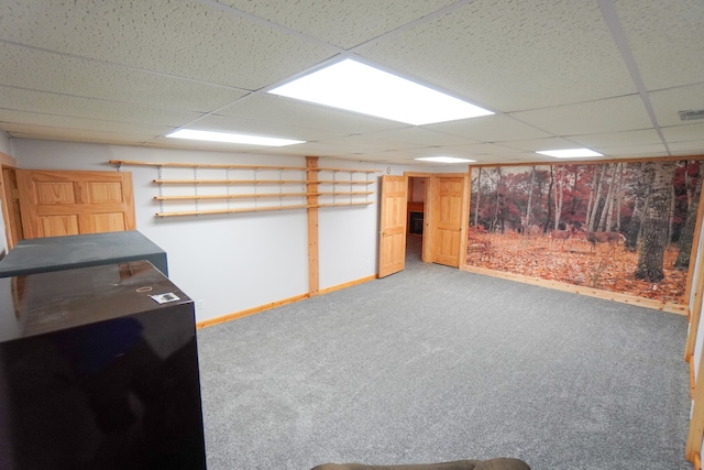 basement with a paneled ceiling and carpet flooring