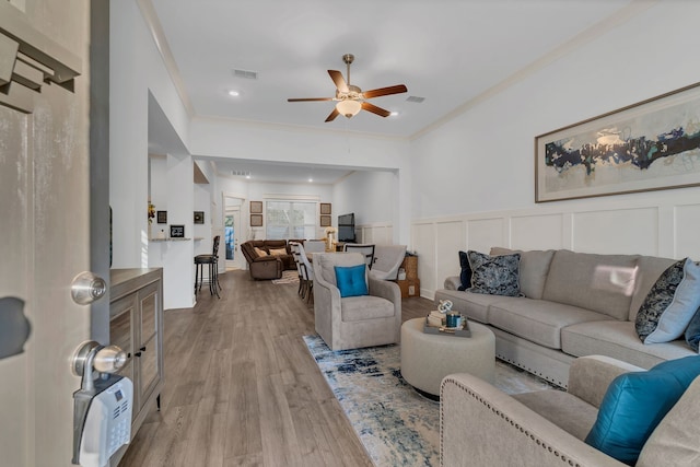 living room with ceiling fan, light hardwood / wood-style floors, and ornamental molding