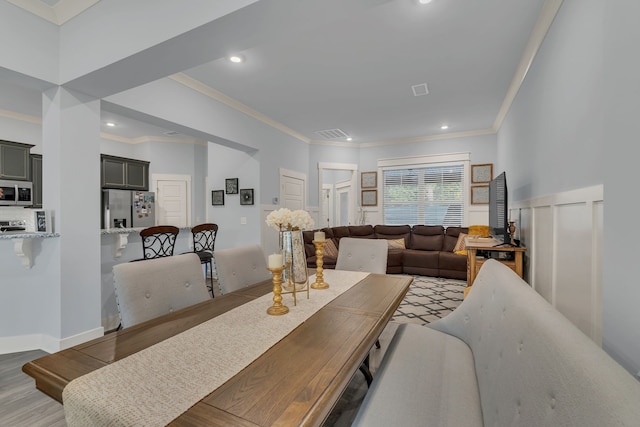 dining space with light hardwood / wood-style floors and crown molding