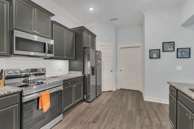 kitchen featuring light stone countertops, tasteful backsplash, ornamental molding, stainless steel appliances, and dark wood-type flooring