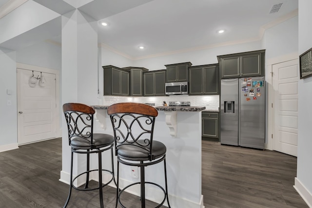 kitchen with a breakfast bar, dark stone counters, a kitchen island, dark hardwood / wood-style flooring, and stainless steel appliances