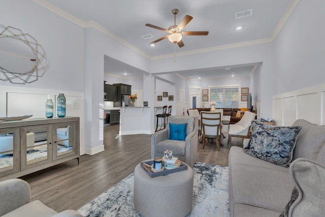 living room with dark hardwood / wood-style floors, ceiling fan, and ornamental molding