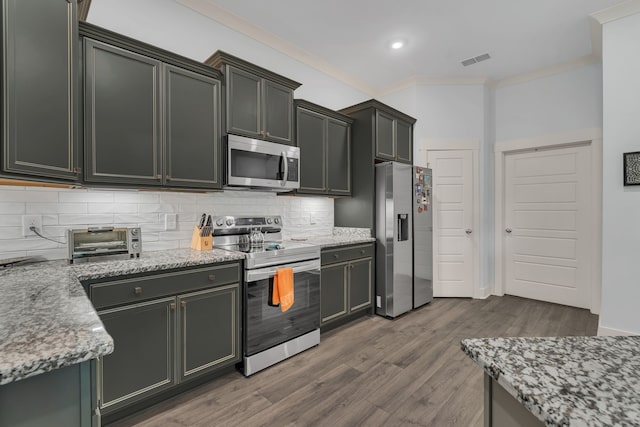 kitchen featuring light stone counters, crown molding, dark wood-type flooring, and appliances with stainless steel finishes