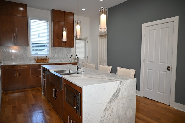 kitchen with decorative light fixtures, sink, a center island with sink, and dark hardwood / wood-style flooring