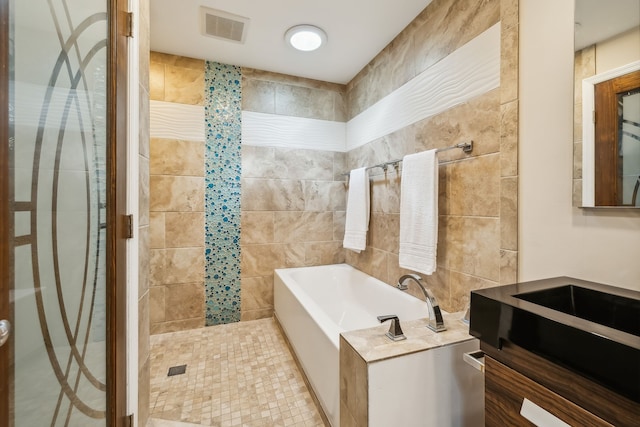 bathroom with tile walls, vanity, and independent shower and bath