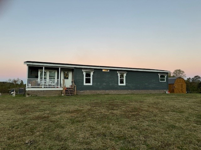 view of front of property with a shed, a porch, and a lawn