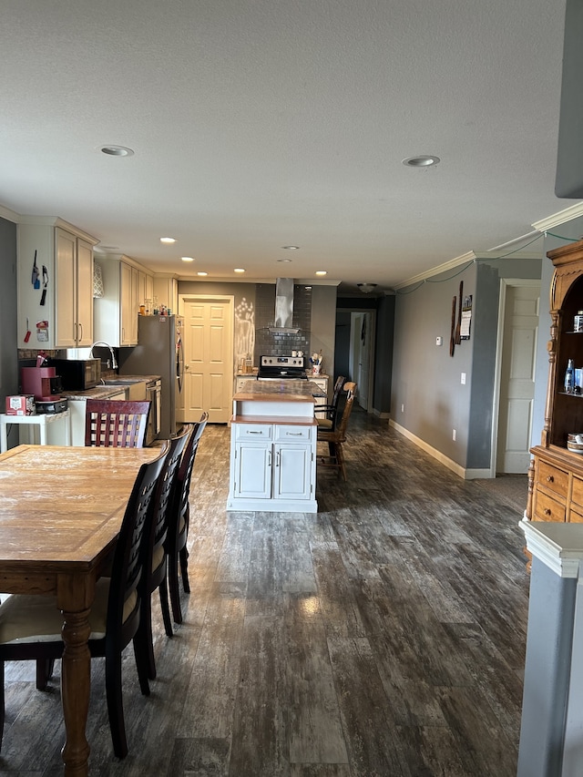 dining room featuring dark wood-type flooring, a textured ceiling, ornamental molding, and sink