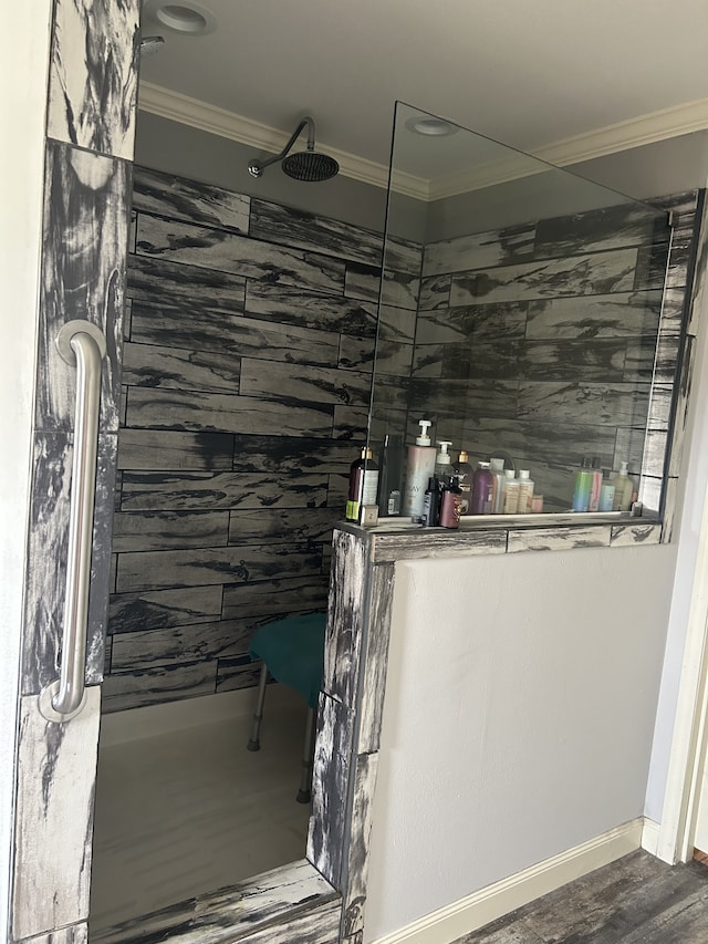 bathroom with a tile shower, crown molding, and hardwood / wood-style flooring