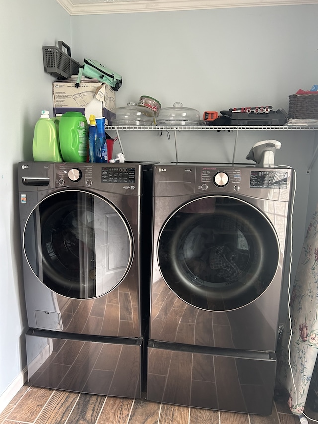 washroom featuring ornamental molding, washing machine and clothes dryer, and wood-type flooring