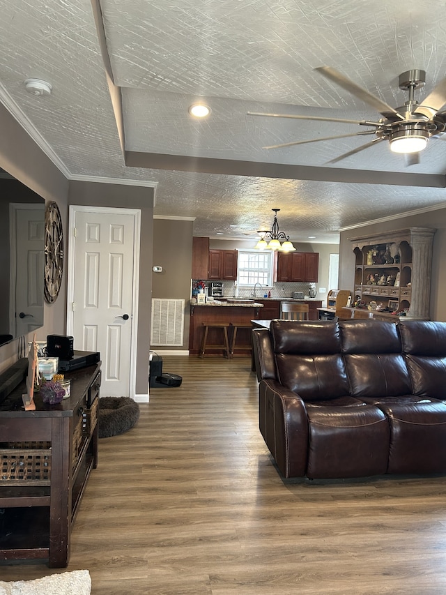 living room with hardwood / wood-style flooring, a textured ceiling, ornamental molding, and ceiling fan with notable chandelier