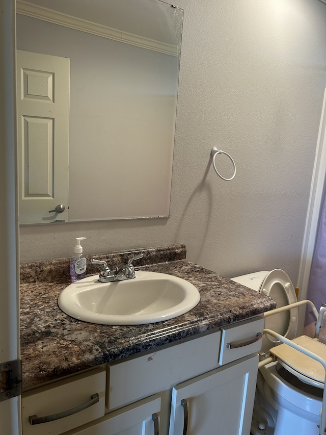 bathroom featuring vanity, crown molding, and toilet