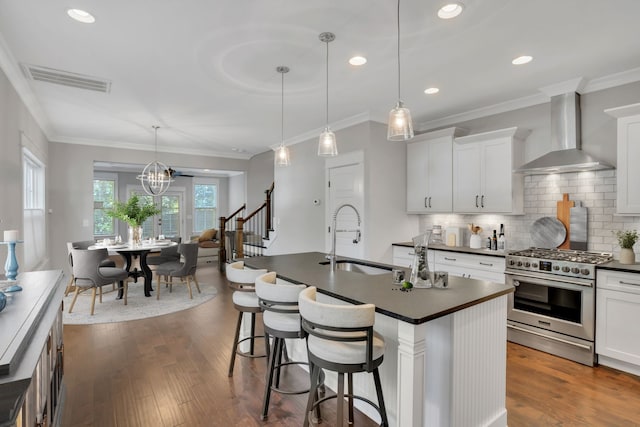 kitchen featuring high end stove, dark hardwood / wood-style flooring, a kitchen island with sink, wall chimney exhaust hood, and sink