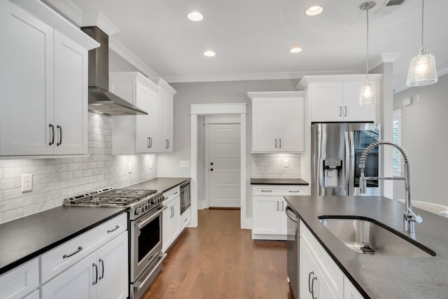 kitchen with wall chimney range hood, white cabinets, hanging light fixtures, and stainless steel appliances