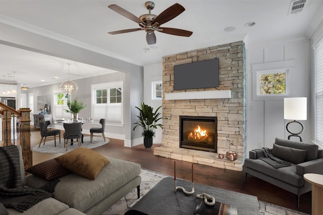 living room with ceiling fan with notable chandelier, crown molding, wood-type flooring, and a fireplace