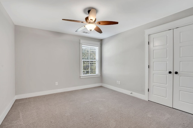 unfurnished bedroom featuring a closet, light colored carpet, and ceiling fan