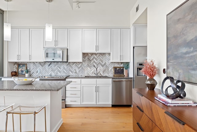 kitchen featuring white cabinetry, stainless steel appliances, sink, and pendant lighting