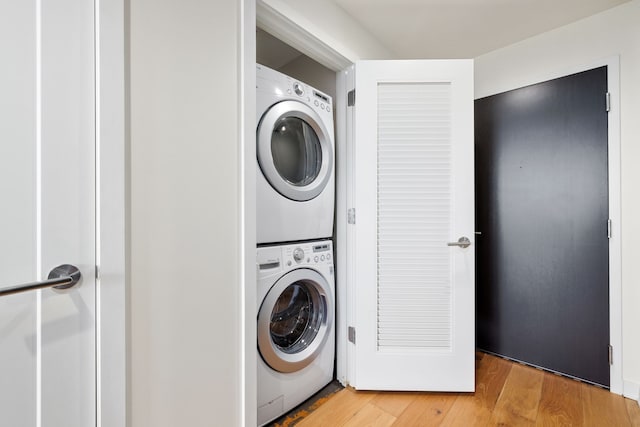 laundry area featuring stacked washing maching and dryer and light hardwood / wood-style floors