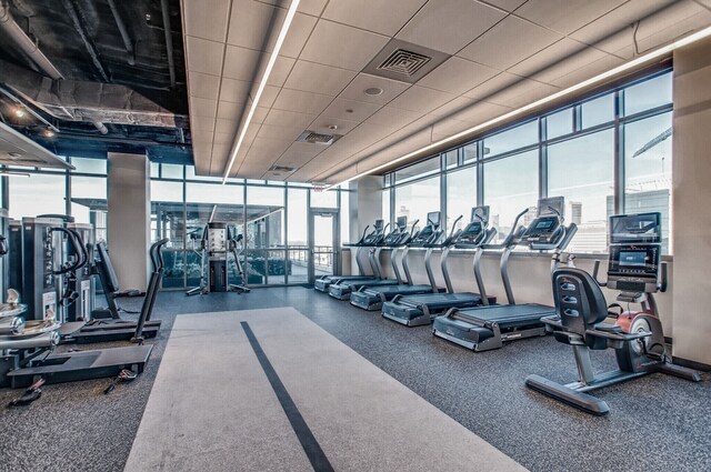 gym with a wall of windows and a paneled ceiling