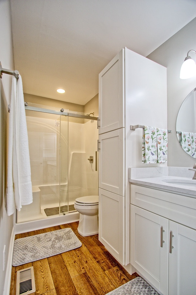 bathroom featuring vanity, toilet, a shower with door, and hardwood / wood-style floors