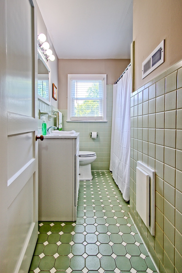 bathroom featuring radiator heating unit, tile walls, toilet, vanity, and curtained shower