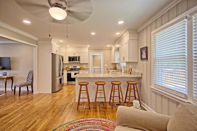 kitchen featuring sink, appliances with stainless steel finishes, white cabinetry, and light hardwood / wood-style floors