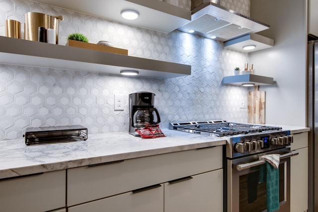 kitchen with white cabinetry, decorative backsplash, light stone countertops, and high end stainless steel range