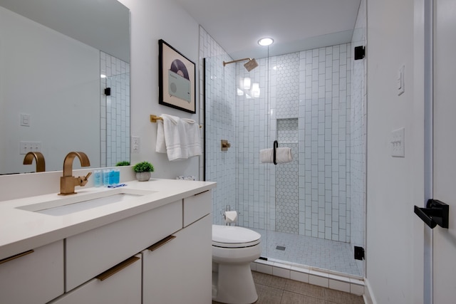 bathroom with a shower with door, vanity, toilet, and tile patterned floors