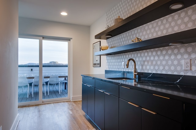 kitchen with a water view, tasteful backsplash, sink, and light wood-type flooring