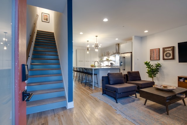 living room featuring an inviting chandelier, sink, and light hardwood / wood-style floors