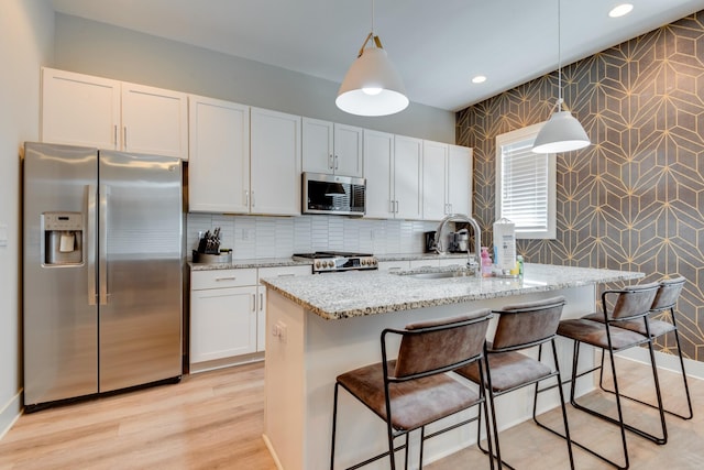 1112 Harmony Way, Nashville, TN 37207 - kitchen with stainless steel appliances, wallpapered walls, light stone countertops, a breakfast bar area, and hanging light fixtures