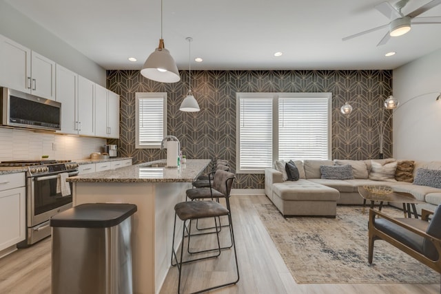 1112 Harmony Way, Nashville, TN 37207 - kitchen with appliances with stainless steel finishes, wallpapered walls, light stone countertops, white cabinets, and a breakfast bar
