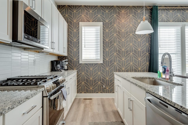 1112 Harmony Way, Nashville, TN 37207 - kitchen with appliances with stainless steel finishes, wallpapered walls, white cabinets, light wood-type flooring, and light stone counters