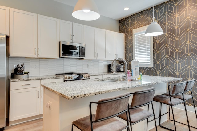 1112 Harmony Way, Nashville, TN 37207 - kitchen featuring stainless steel microwave, range, light stone counters, a breakfast bar area, and white cabinets