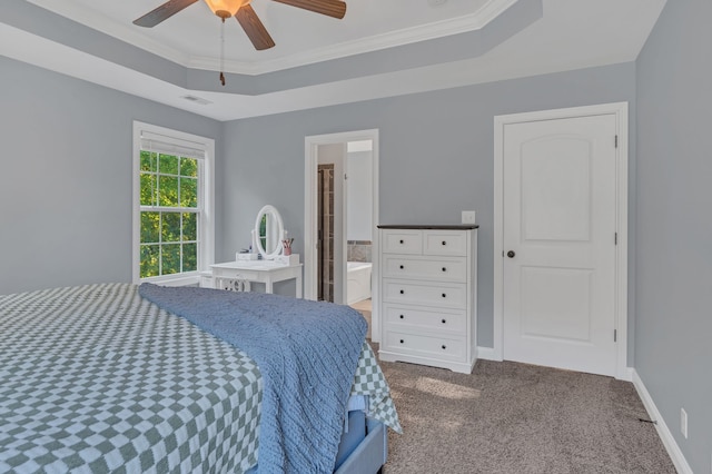 carpeted bedroom with crown molding, ceiling fan, a tray ceiling, and ensuite bath