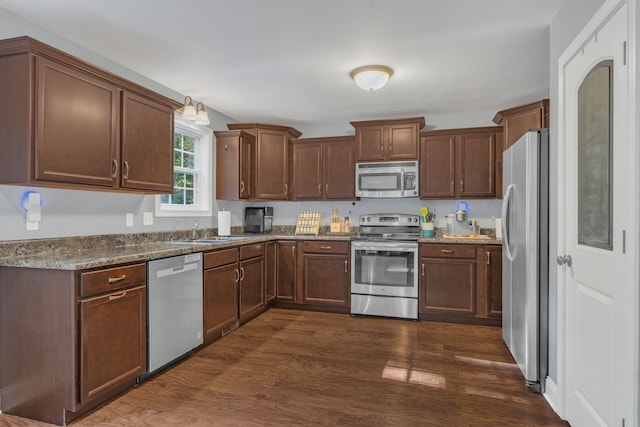 kitchen featuring sink, stainless steel appliances, dark hardwood / wood-style floors, and dark stone countertops