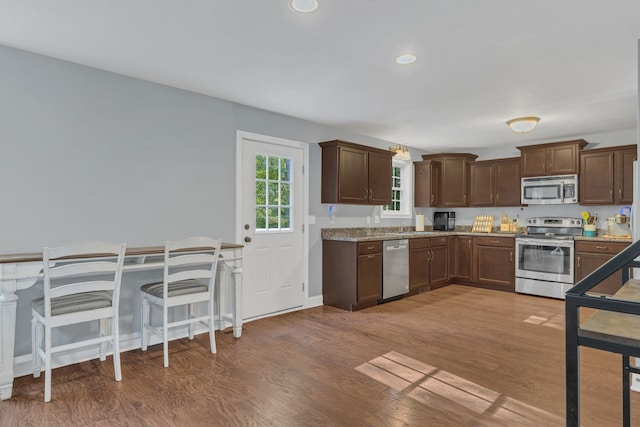 kitchen featuring stainless steel appliances, light stone countertops, sink, and dark hardwood / wood-style floors