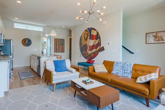 living room with light hardwood / wood-style floors, an inviting chandelier, and sink