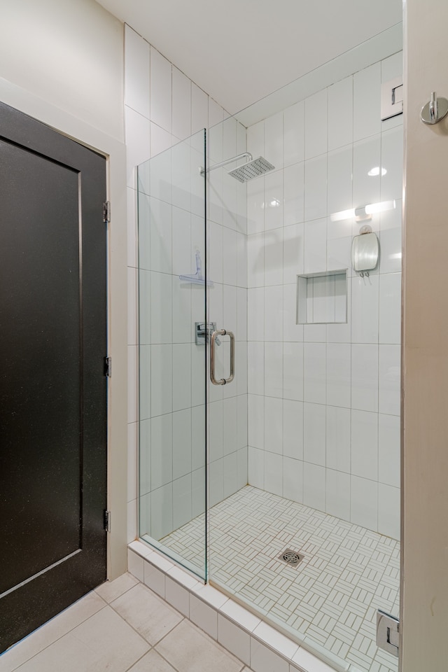 bathroom with a shower with door and tile patterned flooring