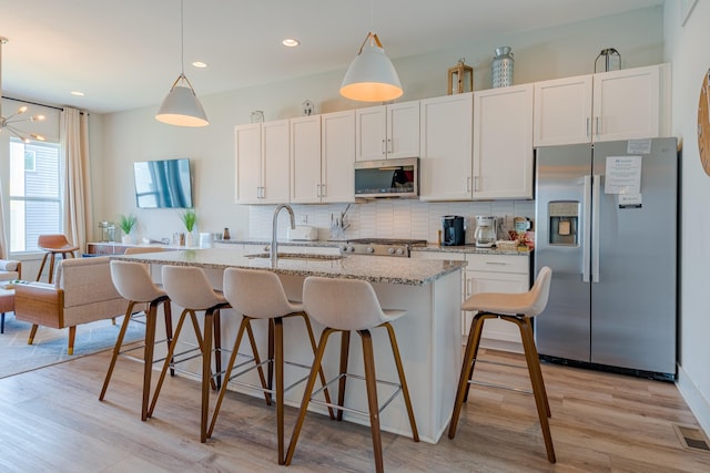 1149 Harmony Way, Nashville, TN 37207 - kitchen with appliances with stainless steel finishes, decorative backsplash, light wood-style floors, a kitchen island with sink, and light stone counters