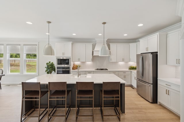 kitchen featuring decorative light fixtures, custom range hood, white cabinets, and appliances with stainless steel finishes