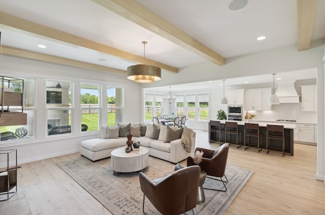 living room featuring a notable chandelier, beam ceiling, and light hardwood / wood-style floors