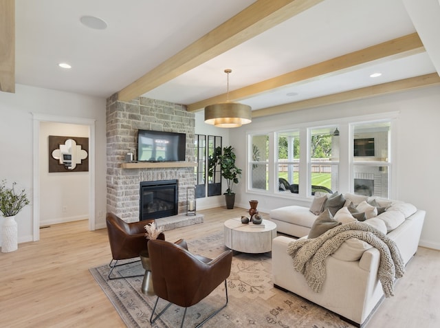 living room featuring a fireplace, light hardwood / wood-style flooring, and beamed ceiling